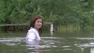 Online film girl with fully clothes swims in lake