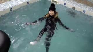 Online film wetlook girl with winter clothes swims in the pool