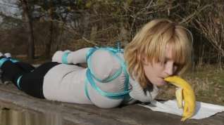 Online film Cute girl eats banana while tied outside