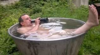 Online film Naked old man rolls around in outside bath tub.